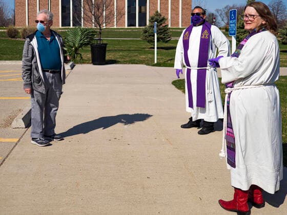 Coronavirus in den USA, Drive-Through Gottesdienst zum Auftakt der Karwoche in Des Moines, Iowa April 5, 2020, Des Moines, Iowa, U.S: Rev. BONNIE PARKER, right, and Rev. RUSSELL LACKEY, center, talk to a parishioner after a drive through Palm Sunday service sponsored by Luther Memorial Church on the campus of Grand View University in Des Moines. About 150 people attended the service. They remained in their cars while the ministers read a short passage from the Bible, handed out palms and blessed them. On Sunday, 05 April, Iowa reported 868 confirmed cases of the Novel Coronavirus (SARS-CoV-2) and COVID-19. There have been 22 deaths attributed to COVID-19 in Iowa. Restaurants, bars, movie theaters, places that draw crowds are closed until 30 April. The Governor has not ordered shelter in place but several Mayors, including the Mayor of Des Moines, have asked residents to stay in their homes for all but essential needs. People are - ZUMAk94_ 20200405_zaf_k94_023 Copyright: xJackxKurtzx