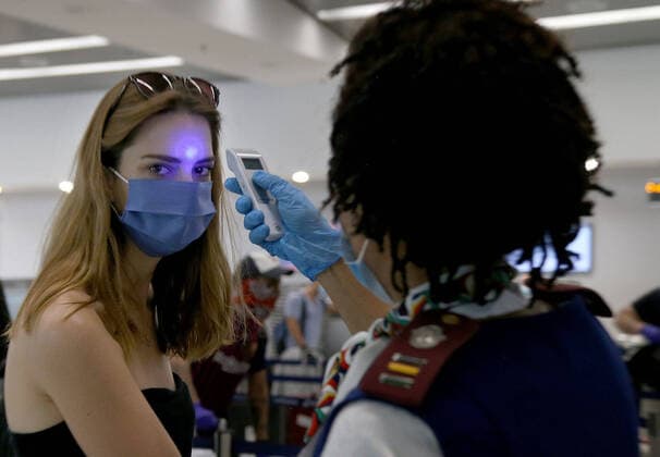 April 14, 2020, Miami, FL, USA: Rosemary Arends, an assistant nurse-flight attendant, checks the temperature of passenger Paula Brooks, part of group of South African nationals at Miami International Airport boarding a special charter flight by South African Airways. Amid the coronavirus pandemic, the flight will repatriate more than 300 South African workers who were supposed to spend these months working at South Florida hotels and resorts, on Tuesday, April 14, 2020. Miami USA - ZUMAm67_ 20200414_zaf_m67_032 Copyright: xPedroxPortalx