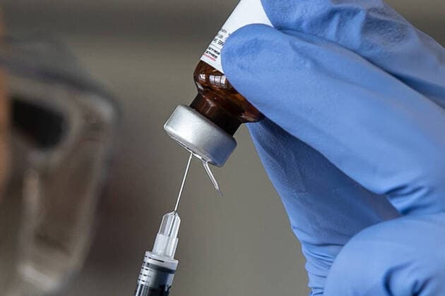 Hannover, Coronavirus, 29.04.2020, Ministerpräsident Stephan Weil und Minister Björn Thümler besuchen die Tierärztliche Hochschule in Hannover Präsident Dr. Gerhard Greif und weitere Wissenschaftler werden dort ihre Forschungen zur Entwicklung eines Impfstoffes gegen Corona vorstellen. Unter anderem geht es um Impfstoffentwicklung und Testung, Labor, SARS-CoV 2, Impfstoff, Spritze, impfen, Laborassistent in Schutzanzug und Maske mit Impfstoffampulle, Symbolfoto,