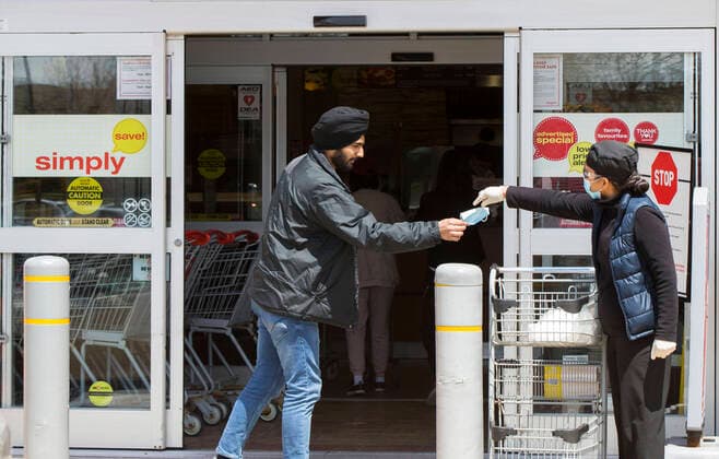 (200504) -- MISSISSAUGA (CANADA), May 4, 2020 -- A staff member (R) hands a face mask to a customer at the entrance of a Longo s in Mississauga, Ontario, Canada, on May 4, 2020. Some provinces in Canada on Monday started easing some of their COVID-19 restrictions following a weekend over which thousands more cases were identified and hundreds more deaths reported. As of Monday afternoon, Canada recorded 60,650 COVID-19 cases, including 3,842 deaths, after the country had implemented lockdown measures against the COVID-19 pandemic for almost two months, according to a CTV News tally. Global COVID-19 deaths surpassed 250,000 on Monday afternoon, reaching 250,134 as of 4:40 p.m. (2040 GMT), according to the Center for Systems Science and Engineering at Johns Hopkins University. (Photo by Xinhua) CANADA-ONTARIO-MISSISSAUGA-COVID-19-MEASURES