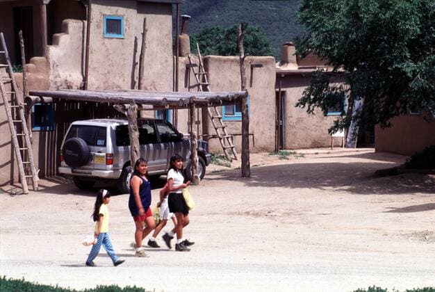 IMAGO Cultures of the world, Taos Pueblo in New Mexico, USA 1 Reisen: Indianerkinder in Taos Pueblo in New Mexico, Indianerdorf der Taos Indianer, erdfarbener Adobe Baustil (Stroh, Erde & Wasser), ca. 150 Menschen wohnen dort dauerhaft, Ureinwohner Nordamerikas, Holz, Holzstäbe, Bohlen, Taos Indian Nation, Reise, Attraktion, Sehenswürdigkeit, Urlaub, Tourismus, bekannte Touristengegend, Touristenort, Urlaubsort, Touristenattraktion, Reiseziel, Urlaubsziel, Sehenswürdigkeit, Holzleiter, Leiter, Indianer, Kinder, Mädchen, Indianermädchen, Amerika, Kult, Sitte, Kultur, Kultstätte, Taos Pueblo New Mexico United States Of America Copyright: xBriganiArt ArtistxAtxWork Heinrix 00024059_00024059