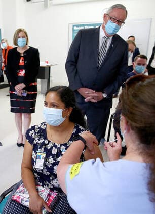 NSW COVID19 VACCINE ROLLOUT, Gayathry Vellangalloor Srinivasan, an Environmental Services Supervisor, is watched by NSW Chief Medical Health Officer Kerry Chant (left) and NSW Health Minister Brad Hazzard (right) as she receives the states first Pfizer vaccination at the Royal Prince Alfred Hospital Vaccination Hub in Sydney, Monday, February 22, 2021. Australia will begin its roll out of the Pfizer coronavirus vaccine on Monday, the country s most complicated logistical exercise to date. ( NO ARCHIVING, EDITORIAL USE ONLY, NO USE IN BOOKS WITHOUT CONSENT SYDNEY NSW AUSTRALIA Copyright: xTobyxZernax 20210222001522236325