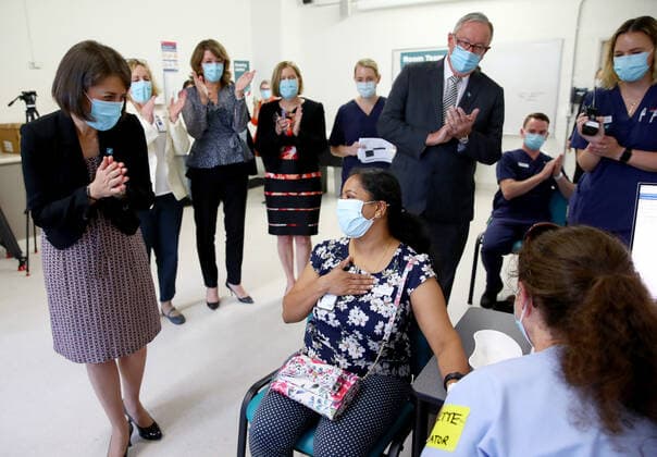 NSW COVID19 VACCINE ROLLOUT, Gayathry Vellangalloor Srinivasan, an Environmental Services Supervisor, is watched by NSW Premier Gladys Berejiklian (left), NSW Chief Medical Health Officer Kerry Chant (fifth right) and NSW Health Minister Brad Hazzard (third right) as she receives the states first Pfizer vaccination at the Royal Prince Alfred Hospital Vaccination Hub in Sydney, Monday, February 22, 2021. Australia will begin its roll out of the Pfizer coronavirus vaccine on Monday, the country s most complicated logistical exercise to date. ( NO ARCHIVING, EDITORIAL USE ONLY, NO USE IN BOOKS WITHOUT CONSENT SYDNEY NSW AUSTRALIA Copyright: xTobyxZernax 20210222001522236535