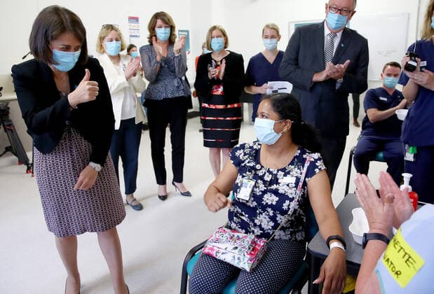 NSW COVID19 VACCINE ROLLOUT, Gayathry Vellangalloor Srinivasan, an Environmental Services Supervisor, is watched by NSW Premier Gladys Berejiklian (left), NSW Chief Medical Health Officer Kerry Chant (second right) and NSW Health Minister Brad Hazzard (right) as she receives the states first Pfizer vaccination at the Royal Prince Alfred Hospital Vaccination Hub in Sydney, Monday, February 22, 2021. Australia will begin its roll out of the Pfizer coronavirus vaccine on Monday, the country s most complicated logistical exercise to date. ( NO ARCHIVING, EDITORIAL USE ONLY, NO USE IN BOOKS WITHOUT CONSENT SYDNEY NSW AUSTRALIA Copyright: xTobyxZernax 20210222001522248548