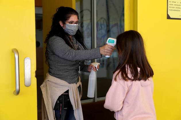 Coronavirus in Portugal, Lockerungen in Lissabon March 15, 2021, Lisbon, Portugal: An education assistant wearing a face mask checks a student s body temperature upon arrival at at Gomes Freire de Andrade school as students return to classes after a period of mandatory lockdown due to the Covid-19 pandemic, in Oeiras, Portugal, on March 15, 2021. Portuguese Government set out a four stages plan to ease COVID-19 restrictions, as the vaccination program progresses, with the first stage beginning on March 15 with reopening of nurseries, kindergartens and elementary schools, as well as hairdressers, barbers and bookstores. Lisbon Portugal - ZUMAf123 20210315_zap_f123_006 Copyright: xPedroxFiuzax