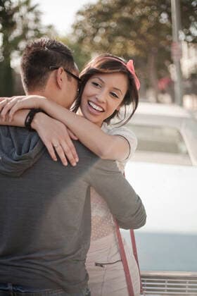 Smiling girlfriend embracing boyfriend standing against car model released Symbolfoto AJOF01247