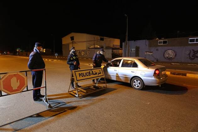 March 27, 2021, Deir Al-Balah, Gaza Strip, Palestinian Territory: Palestinian policemen wear face masks, guard a barrier blocking a road, in Deir Al-Balah in the center of the Gaza Strip, on March 27, 2021, after the Ministry of Interior in Gaza City announced the full lockdown on Saturday all over the Gaza Strip at night-time from 9:00 PM, after the increase in cases infected with Coronavirus Deir Al-Balah Palestinian Territory - ZUMAap3_ 20210327_zaf_ap3_208 Copyright: xAshrafxAmrax