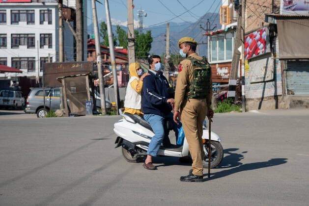 April 25, 2021, Srinagar, Jammu and Kashmir, India: An Indian policeman stops a man on a scooter during a one day curfew to curb the spread of COVID-19 in Srinagar..India has reported 346,786 new cases of COVID-19 for the previous 24 hours, with 2,624 deaths, the world™s highest daily toll since the pandemic begun last year. Overall, nearly 190,000 people have died from COVID in the country, while more than 16.6 million have been infected. Srinagar India - ZUMAs197 20210425_zaa_s197_065 Copyright: xIdreesxAbbasx