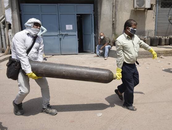 MANESAR, INDIA - APRIL 28: Family members of a Covid-19 patient arrive to refill an empty oxygen cylinder outside a filling center on April 28, 2021 in Manesar, India. India, in the last 24 hours, recorded 3,60,960 fresh Covid-19 cases and 3,293 deaths, which is the highest in the country so far. With today?s numbers, the total number of coronavirus cases rose to 1,79,97,267 and the number of fatalities reached 2,01,187. At present, there are 29,78,709 active cases in India and as many as 1,48,17,371 people have recovered. As Covid-19 cases continued to surge in India people are struggling to get hospital beds, ventilators, oxygen cylinders, injections and medicines with the health infrastructure in the state almost stretched to its limit