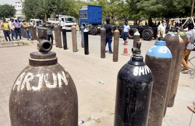 MANESAR, INDIA - APRIL 28: Family members of Covid-19 patients waiting to refill empty oxygen cylinders outside a filling center on April 28, 2021 in Manesar, India. India, in the last 24 hours, recorded 3,60,960 fresh Covid-19 cases and 3,293 deaths, which is the highest in the country so far. With today?s numbers, the total number of coronavirus cases rose to 1,79,97,267 and the number of fatalities reached 2,01,187. At present, there are 29,78,709 active cases in India and as many as 1,48,17,371 people have recovered. As Covid-19 cases continued to surge in India people are struggling to get hospital beds, ventilators, oxygen cylinders, injections and medicines with the health infrastructure in the state almost stretched to its limit.