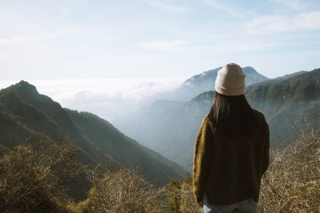Back view of unrecognizable woman in warm clothes standing alone on viewpoint and looking at foggy mountain ridges covered fluffy clouds in Sequoia National Park under blue sky in USA, Model released Copyright: xLeirexUnzuetax MR