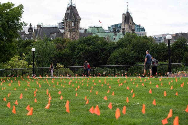 July 1, 2021, Ottawa, on, Canada: Parliament Hill s East Block is seen as people walk beside orange flags, representing children who died while attending Indian residential schools in Canada, placed in the grass at Major s Hill Park in Ottawa, on Canada Day, Thursday, July 1, 2021. Ottawa Canada - ZUMAc35_ 20210701_zaf_c35_003 Copyright: xJustinxTangx