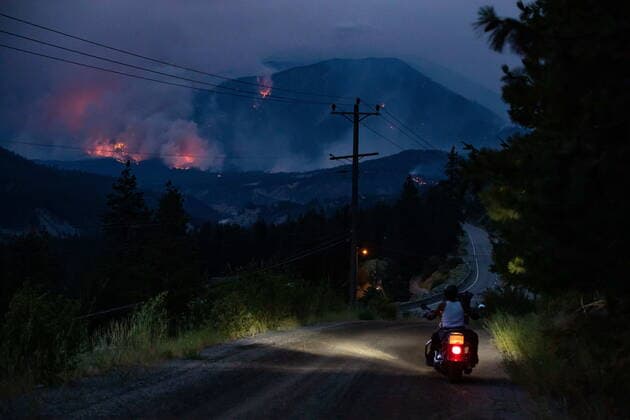 July 1, 2021, Lytton, BC, Canada: Alfred Higginbottom, of the Skuppah Indian Band, a Nlaka pamux First Nations government, rides off on his motorcycle after stopping to watch a wildfire burn on the side of a mountain in Lytton, B.C., Thursday, July 1, 2021. Lytton Canada - ZUMAc35_ 20210701_zaf_c35_307 Copyright: xDarrylxDyckx