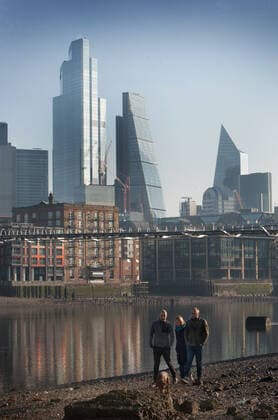 February 27, 2021, London, United Kingdom: People walk their dog on the Thames foreshore with a backdrop of London s city skyline viewed from the riverbank at low tide..The river banks gradually grow as the Thames reaches low tide. The beaches well known to mudlarkers and beachcombers and only visible for a couple of hours a day are giving Londoners, over a year into lockdown, somewhere different to walk and explore. London United Kingdom - ZUMAs197 20210227_zab_s197_032 Copyright: xMartinxPopex