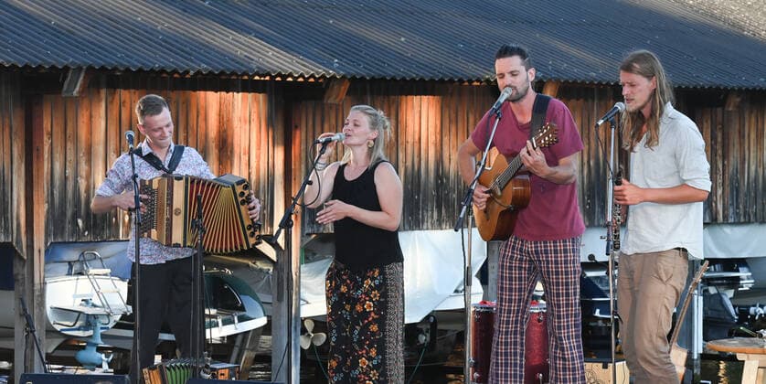 Konzert der Peter Mayer Hofkapelle, In der Bootswerft Frauscher in Gmunden, im Rahmen der Salzkammergut Festwochen Gmunden, am 09.07.21. Das Bild zeigt v.l.n.r.: Andreas Jamnik, Steirische Harmonika und Gesang, Nora Mayer, Gesang und Perkussion, Peter Mayer, Gitarre und Gesang, Michl Dumfarth, Klarinette und Gesang 2021 - Konzert der Peter Mayer Hofkapelle, In der Bootswerft Frauscher in Gmunden, im Rahmen der Salzkammergut Festwochen Gmunden, am 09.07.21