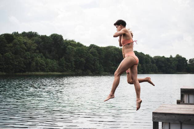 IMAGO Creative: Jahreszeit Sommer, Festivals Friends jumping in lake in Poland in orange swimsuit in summer Garbicz, Lubusz Voivodeship, Poland CR_PIDODS210721-787655-01 ,model released, Symbolfoto