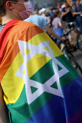 Berliner CHRISTOPHER STREET DAY 2021 - CSD - Am 24. Juli 2021 zieht der CSD in Berlin unter dem Motto SAVE OUR COMMUNITY SAVE YOUR PRIDE zum 43. Mal durch die Hauptstadt. Demoteilnehmer vor dem Brandenburger Tor trägt Regenbogenflagge mit einem Davidstern. Die bunte CSD-Parade startete in diesem Jahr als Demonstration an der Leipziger Straße, führte über den Potsdamer Platz, vorbei am Denkmal für die im Nationalsozialismus verfolgten Homosexuellen zum Brandenburger Tor und über die Siegessäule zur Urania. Aufgrund der Corona-Pandemie fand die Demonstration ausschließlich unter Einhaltung der vom Berliner Senat erlassenen Vorgaben statt. Die in den Vorjahren übliche Abschlusskundgebung musste daher ausfallen.