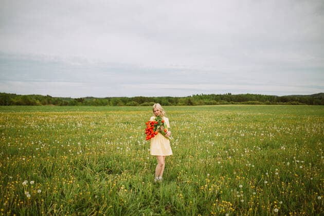 Content female in dress standing with bunch of red tulip flowers in meadow in summer CamilleGirard_GirlWithTulips_16.jpg Copyright: xCamillexGirardx Model Released