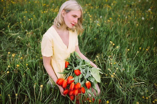 Content female in dress standing with bunch of red tulip flowers in meadow in summer CamilleGirard_GirlWithTulips_24.jpg Copyright: xCamillexGirardx Model Released