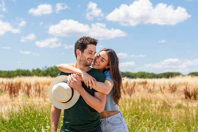 Smiling girlfriend embracing boyfriend at meadow on sunny day model released Symbolfoto EIF01632