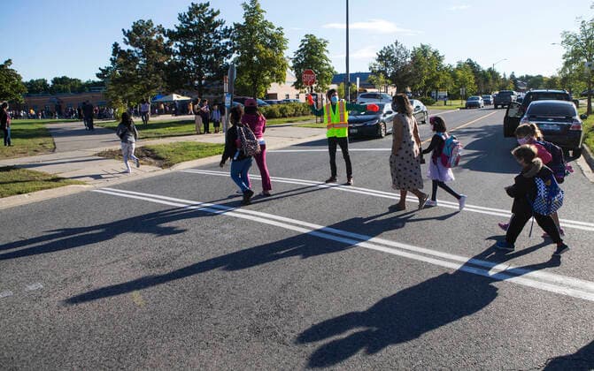 (210909) -- MISSISSAUGA (CANADA), Sept. 9, 2021 -- A crossing guard wearing a face mask works on a street outside a school in Mississauga, the Greater Toronto Area, Ontario, Canada, on Sept. 9, 2021. Schools in Toronto, Peel, York and Durham started their school years on Thursday, offering a mix of in-person classes and online learning for students. (Photo by Xinhua) CANADA-ONTARIO-MISSISSAUGA-COVID-19-SCHOOL-OPENING DAY ZouxZheng