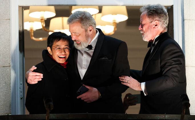 OSLO, NORWAY – DECEMBER 10, 2021: Nobel Peace Prize winners, Filipino-American journalist, co-founder and CEO of Rappler Maria Ressa, Russian journalist, Novaya Gazeta editor-in-chief Dmitry Muratov, and World Food Programme Executive Director David Beasley (L-R) greet the participants in a torchlight parade in honour of the Nobel Peace Prize winners from a balcony of the Grand Hotel. The Norwegian Nobel Committee has decided to award the Nobel Peace Prize for 2021 to Filipino-American journalist, co-founder and CEO of Rappler Maria Ressa and Russian journalist, Novaya Gazeta editor-in-chief Dmitry Muratov in recognition of their efforts to safeguard freedom of expression, which is a precondition for democracy and lasting peace . The World TS11B68D