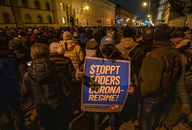 Querdenker-Demo, Ludwigstraße, München 15. Dezember 2021 DEU, Deutschland, München, 15.12.2021, grosse Kundgebung von Corona-Rebellen gegen Coronamassnahmen und Impfpflicht, Dezember 2021, Querdenker Demo, ca. 3500 DemonstrantInnen, Ludwigstrasse, Ecke Schellingstrasse, AfD-Sympathisant, Plakat Stoppt Söders Corona-Regime, abends, Bayern, Dezember, Querformat