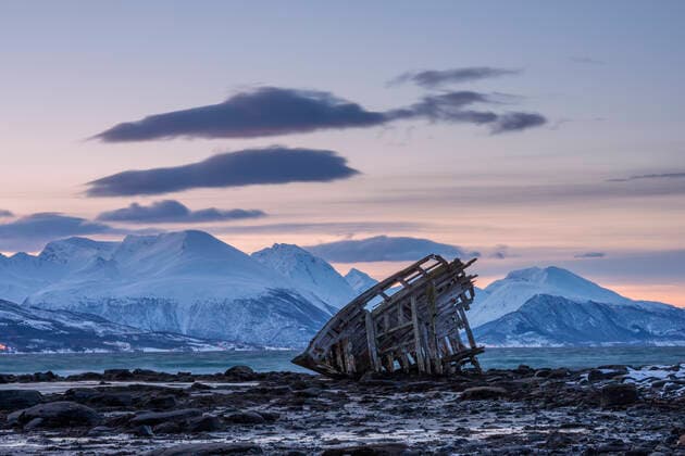 Shipwreck lying on shore of secluded Fjord at winter dawn, RUEF03444
