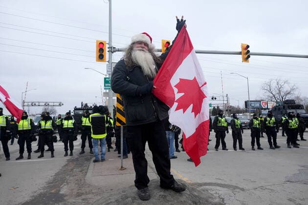 February 12, 2022, Windsor, ON, CANADA: A protester flashes the peace sign as police officers enforce an injunction against their demonstration, which has blocked traffic across the Ambassador Bridge by protesters against COVID-19 restrictions, in Windsor, Ont., Saturday, Feb. 12, 2022. Windsor CANADA - ZUMAc35_ 20220212_zaf_c35_114 Copyright: xNathanxDenettex