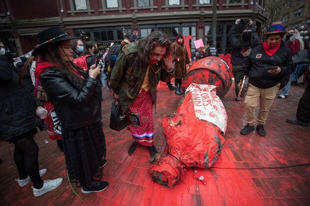 February 14, 2022, VANCOUVER, BC, CANADA: A person spits on the Gassy Jack statue after it was toppled and covered in red paint during the annual Women s Memorial March, in Vancouver, on Monday, February 14, 2022. The statue is a monument to Gassy Jack Deighton, a Vancouver saloon owner in the 1860s, whom Vancouver s Gastown neighbourhood is named after. The march is held to honour missing and murdered women and girls from the community with stops along the way to commemorate where women were last seen or found. VANCOUVER CANADA - ZUMAc35_ 20220214_zaf_c35_172 Copyright: xDarrylxDyckx