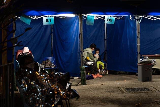 Hong Kong s COVID-19 Infections Soar On February 16, 2022, in a temporary shelter outside Caritas Medical Center in Hong Kong, China, a patient lies in a hospital bed waiting for medical treatment. The temperature drops at night, the patient is put on thermal insulation products, and a father feeds his son. The Food and Health Bureau confirmed a new record of 4,285 infections, while 7,000 people initially tested positive, a near-record high. At least 12,000 infected people are waiting to be admitted to hospitals as COVID-19 cases overwhelm the public health system. Hong Kong China Copyright: xLeungxManxHeix originalFilename: manhei-notitle220216_npWA9.jpg