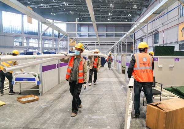 (220408) -- SHANGHAI, April 8, 2022 -- Workers work at the construction site of a temporary hospital at the National Exhibition and Convention Center (Shanghai) in east China s Shanghai, April 8, 2022. Shanghai has opened and will continue to construct more temporary hospitals to enhance the city s treatment capacity for COVID-19 infections in its latest COVID-19 resurgence, authorities said Friday. Four municipal-level temporary hospitals, three located in Pudong District and one in Chongming District, have been put into use as of Friday. Covering a total of 500,000 square meters, the four sites can offer a total of 38,000 beds, said Jin Chen, deputy director of Shanghai s housing and urban-rural development management committee.
