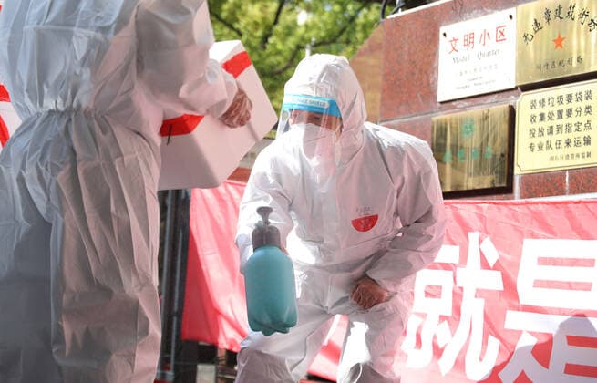 (220412) -- SHANGHAI, April 12, 2022 -- Shi Zhongliang (R) sprays disinfectants on newly-arrived parcels at the entrance of his residential community in east China s Shanghai, April 11, 2022. Shi Zhongliang, a resident of Qibao Township, Minhang District of Shanghai, now renders his service as a volunteer in his community. His residential community has been under closed-off management since March 18 due to the resurgence of COVID-19. Soon after that, Shi joined the community volunteer team spontaneously organized by the residents from the same community. The team, with only seven members from the start, has grown as big as 40 within a month. Shi and his teammates are mainly responsible for delivering the living materials purchased