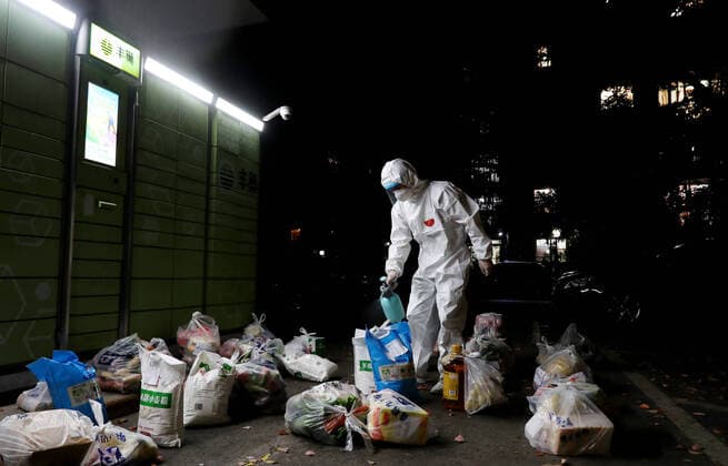 (220412) -- SHANGHAI, April 12, 2022 -- Shi Zhongliang sprays disinfectants on the newly-arrived living materials in the evening in east China s Shanghai, April 11, 2022. Shi Zhongliang, a resident of Qibao Township, Minhang District of Shanghai, now renders his service as a volunteer in his community. His residential community has been under closed-off management since March 18 due to the resurgence of COVID-19. Soon after that, Shi joined the community volunteer team spontaneously organized by the residents from the same community. The team, with only seven members from the start, has grown as big as 40 within a month. Shi and his teammates are mainly responsible for delivering the living materials purchased online by the residen