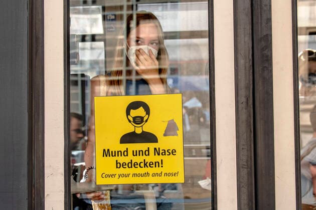 junge Frau mit Maske in der Tram, Schild zur Maskenpflicht in öffentlichen Verkehrsmitteln, München, 13. August 2022 Deutschland, München, 13.08.2022, junge Frau setzt nach dem Einsteigen ihre FFP2-Maske in der Tram auf, Schild Mund und Nase bedecken, Maskenpflicht in öffentlichen Verkehrsmitteln, Öffentlicher Personennahverkehr, Strassenbahn, Münchner Verkehrsgesellschaft, MVG, 9-Euro-Ticket, Monatsticket, Verkehrsmittel, Öffentlicher Nahverkehr, Pandemie, COVID-19, Coronakrise, 2022, Bayern, August, bayerisch,