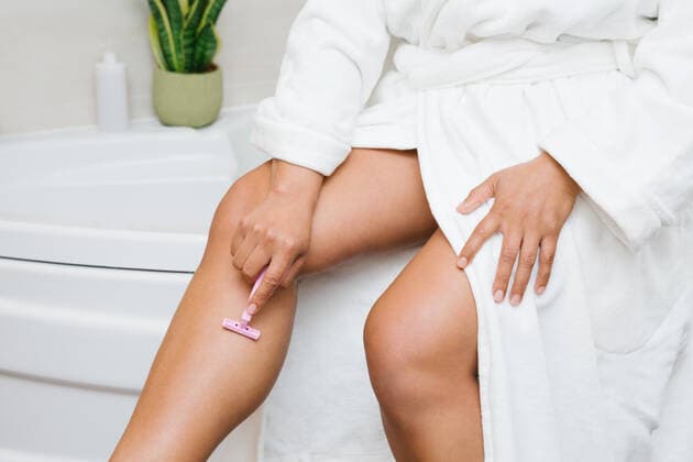 Crop unrecognizable female in bathrobe shaving legs with razor while doing skin care routine in bathroom, Model released AngelaRober_AnnyPersonalCare_31 Copyright: xAngelaxRoberx MR