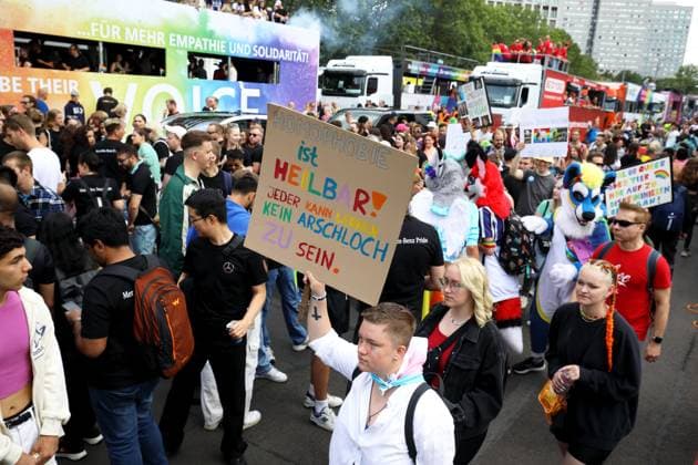 CHRISTOPHER STREET DAY 2023 - BERLIN PRIDE 2023 - CSD Berlin - Am 22. Juli 2023 zieht der CSD in Berlin unter dem bilingualen Motto BE THEIR VOICE AND OURS! ... FÜR MEHR EMPATHIE UND SOLIDARITÄT! zum 45. Mal durch die Hauptstadt. Die bunte CSD-Parade startet als Demonstration an der Leipziger Straße und führt auf einer 7,4 Kilometer langen Strecke über den Potsdamer Platz, vorbei am Nollendorfplatz, über die Siegessäule (Großer Stern) und der Straße des 17. Juni zum Endpunkt am Brandenburger Tor. Die Veranstalter rechnen im Tagesverlauf mit bis zu 500.000 Teilnehmerinnen und Teilnehmern. Demoteilnehmer trägt Protestschild: HOMOPHOBIE ist HEILBAR! - JEDER KANN LERNEN KEIN ARSCHLOCH ZU SEIN.