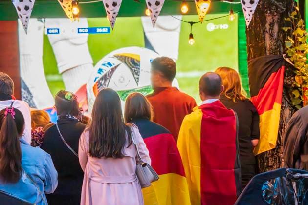 Public Viewing an der Leopoldstraße, Eröffnungsspiel Deutschland gegen Schottland, UEFA EURO 2024, München, 14. Juni 2024 Deutschland, München, 14. Juni 2024, deutsche Fußballfans beim Public Viewing an der Leopoldstraße beim Eröffnungsspiel Deutschland gegen Schottland, Endstand 5:1, hier in der ersten Halbzeit beim Stand von 2:0, Fußballfreunde mit Deutschlandfahnen bei der Live-Übertragung im Außenbereich einer Gastwirtschaft, die Fußball-Europameisterschaft dauert bis zum 14. Juli, Fußball, Sport,
