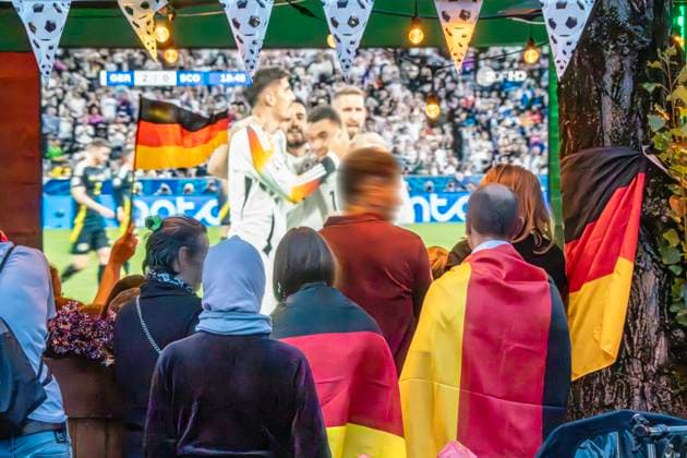 Public Viewing an der Leopoldstraße, Eröffnungsspiel Deutschland gegen Schottland, UEFA EURO 2024, München, 14. Juni 2024 Deutschland, München, 14. Juni 2024, deutsche Fußballfans beim Public Viewing an der Leopoldstraße beim Eröffnungsspiel Deutschland gegen Schottland, Endstand 5:1, hier in der ersten Halbzeit: deutsche Nationalspieler jubeln über das 2:0, Fußballfreunde mit Deutschlandfahnen bei der Live-Übertragung im Außenbereich einer Gastwirtschaft, die Fußball-Europameisterschaft dauert bis zum 14. Juli, Fußball, Sport,
