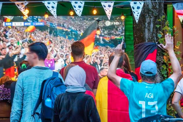 Public Viewing an der Leopoldstraße, Eröffnungsspiel Deutschland gegen Schottland, UEFA EURO 2024, München, 14. Juni 2024 Deutschland, München, 14. Juni 2024, deutsche Fußballfans beim Public Viewing an der Leopoldstraße beim Eröffnungsspiel Deutschland gegen Schottland, Endstand 5:1, hier in der ersten Halbzeit: Zuschauer jubeln über das 1:0 in der 10. Minute, Fußballfreunde mit Deutschlandfahnen bei der Live-Übertragung im Außenbereich einer Gastwirtschaft, die Fußball-Europameisterschaft dauert bis zum 14. Juli, Fußball, Sport,