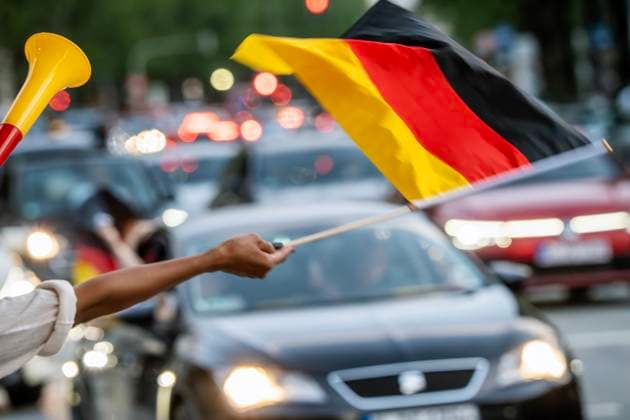 Fußballfans feiern den deutschen Sieg im Spiel gegen Ungarn, Frau schwenkt Deutschlandfahne an der Leopoldstraße, People of Color, München, 19. Juni 2024 Deutschland, München, 19. Juni 2024, Fußballfans feiern den deutschen Sieg im Spiel gegen Ungarn, schwenken Mittwochabend Deutschlandfahnen in der Leopoldstraße, auch Schwarze Menschen, People of Color, Frau steht mit schwarzrotgoldener Fantröte und Deutschlandfahne am Straßenrand, Sommermärchen, Deutschland gegen Ungarn endete 2:0, Fußball-EM, UEFA EURO 2024, Fußball-Europameisterschaft, Fußball, Sport,