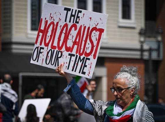 Woman With Israeli Flag Attacked During Edmonton Pro-Palestine Protest EDMONTON, CANADA JUNE 22: A protester holds a placard with words The Holocaust Of Our Time as members of the local Palestinian diaspora, joined by Iranian and other Middle Eastern Muslim protesters, along with local activists, gather on White Avenue in Edmonton for the Hands Off Palestine, Iran, Syria, Yemen, Lebanon protest on June 22, 2025, in Edmonton, Alberta, Canada. Edmonton Canada Copyright: xArturxWidakx originalFilename: widak-womanwit250622_npLhm.jpg