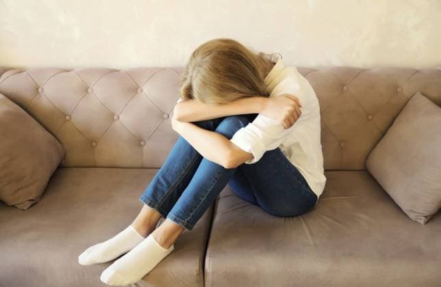 Aufgewühlte, traurige, weinende Frau, die ihre Augen und ihr Gesicht mit den Händen bedeckt, während sie seelisches oder körperliches Leid erfährt, Müdigkeit, die auf der Couch in einem Zimmer zu Hause sitzt Upset sad crying woman covering her eyes and face with her hands while experiencing mental or physical suffering, fatigue sitting on the couch in room at home Copyright: imageBROKER VeronikaxKorneva ibxiqx14269919.jpg ,model released, Symbolfoto ,property released