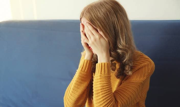 Aufgewühlte, traurige, weinende Frau, die ihre Augen und ihr Gesicht mit den Händen bedeckt, während sie seelisches oder körperliches Leid erfährt, Müdigkeit, die auf der Couch in einem Zimmer zu Hause sitzt Upset sad crying woman covering her eyes and face with her hands while experiencing mental or physical suffering, fatigue sitting on the couch in room at home Copyright: imageBROKER VeronikaxKorneva ibxiqx14270012.jpg ,model released, Symbolfoto ,property released