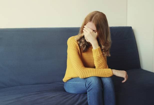 Aufgewühlte, traurige, weinende Frau, die ihre Augen und ihr Gesicht mit den Händen bedeckt, während sie seelisches Leid, Depression und Müdigkeit empfindet, während sie zu Hause auf der Couch sitzt Upset sad crying woman covering her eyes and face with her hands while experiencing mental suffering, depression, fatigue sitting on the couch in room at home Copyright: imageBROKER VeronikaxKorneva ibxiqx14270443.jpg ,model released, Symbolfoto ,property released