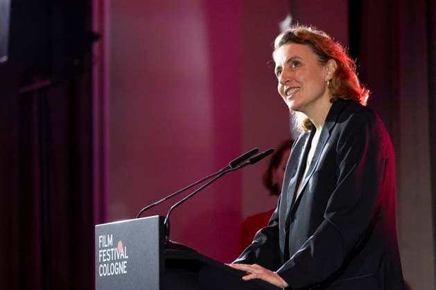 Schauspielerin Maren EGGERT (mi.), Preistraegerin International Actors Award 2025, Portrait, Portraet, Halbfigur, bei ihrer Dankesrede, am Rednerpult, freundlich, lachen, beim Film Festival Cologne, im Filmpalast Koeln, am 16.10.2025.