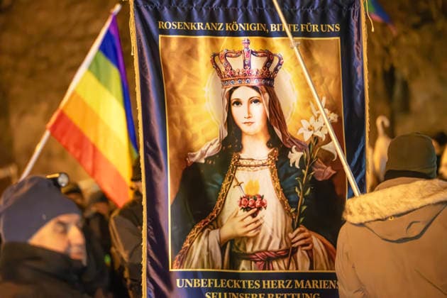 Christlich-fundamentalistischer Protest gegen Dragqueen-Lesung von Vicky Voyage, Lesung für Kinder in der Stadtbibliothek Moosach, München, 1. Dezember 2025 Deutschland, München, 1. Dezember 2025, Protest gegen Dragqueen-Lesung in der Stadtbibliothek Moosach, eine christlich-fiundamentalistische Gruppe protestiert mit einem Marienbild gegen die Lesung, dahinter eine Regenbogenflagge einer Gegendemo gegen Rechts vom Bündnis München ist bunt, Dragqueen Vicky Voyage liest zur gleichen Zeit vor Familien mit Kindern aus Kinderbüchern vor, Proteste vor der Bibliothek in der Hanauer Straße, Montagnachmittag ab 16 Uhr im Stadtteil Moosach,