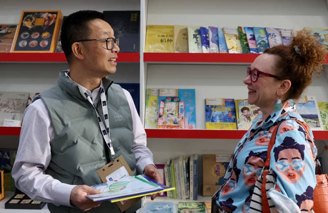 (260311) -- LONDON, March 11, 2026 -- People talk at the China Pavilion of the 2026 London Book Fair in London, Britain, March 10, 2026. At Olympia London, where the 2026 London Book Fair opened Tuesday, the China pavilion stands out not merely for its expansive footprint, but for the comprehensive publishing ecosystem it showcases. The Chinese publishing delegation has arrived with an impressive portfolio of over 4,000 titles and a packed schedule of more than 40 events. Spanning the three-day fair, the agenda ranges from high-profile new book launches and author talks to rights exchanges and industry forums. TO GO WITH Feature: Two-way street -- China s delegation highlights cultural synergy, tech fusion at London Book Fair ) BRI