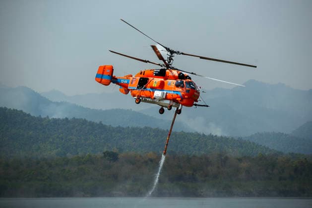 March 27, 2026, Chiang Mai, Thailand: A helicopter performs water pickup operations over a reservoir in Chiang Mai, northern Thailand, as part of aerial firefighting efforts against ongoing wildfires. A KA-32 helicopter from the Department of Disaster Prevention and Mitigation skims the water surface to collect water before heading to fire-affected forest areas amid hazy conditions caused by smoke and rising PM2.5 pollution. Chiang Mai Thailand - ZUMAs197 20260327_aaa_s197_328 Copyright: xPongmanatxTasirix