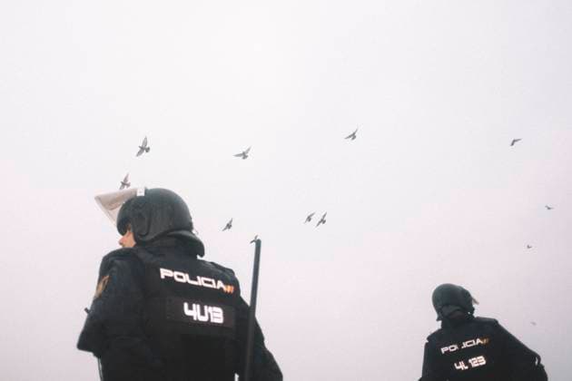 October 4, 2026, Ceuta, Ceuta, Spain: Pigeons fly over riot police officers during the eviction of the makeshift migrant camp on El Trampolin beach in Ceuta. Spanish National Police began evicting the makeshift camp on El Trampolin beach in Ceuta on October 4, where more than 3,000 migrants, most of them young Moroccan men, were living. Dozens of police vans, armoured vehicles of the Police Intervention Units (UIP), drones and boats took part in the operation. People were taken by bus to the temporary centre at the Tarajal border to be identified, and the authorities plan to clear the beach in phases before October 15. The camp grew after a mass arrival at the end of July 2026 set off a migration and political crisis. Ceuta Spain - ZUMAs392 20261004_zip_s392_001 Copyright: xFabianxSuspensivox